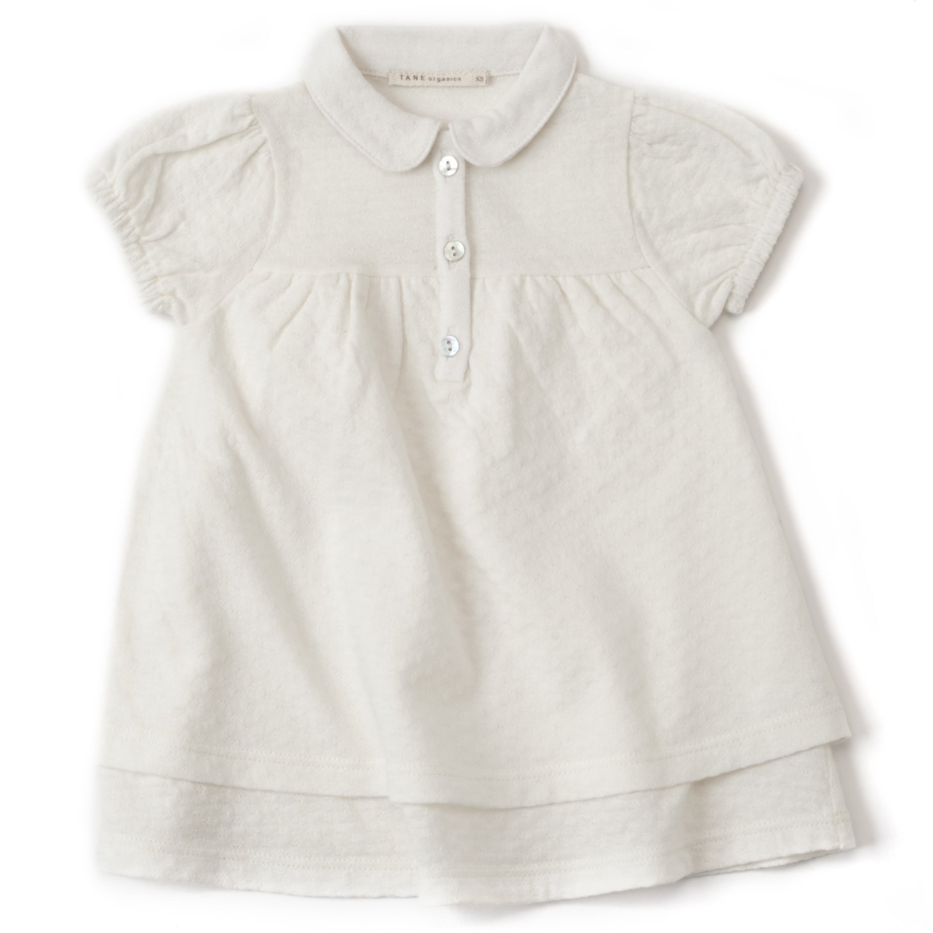 cream color pointelle double layered cap sleeved dress with peter pan collars and 3 natural shell buttons at the center front.  Soft elastics at cuffs with delicate shirrings at the sleeves and the bodice.  100% organic cotton pointelle knit.